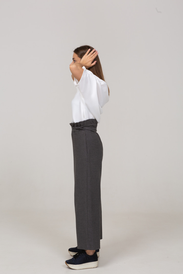 Side view of a young lady in office clothing touching her ears