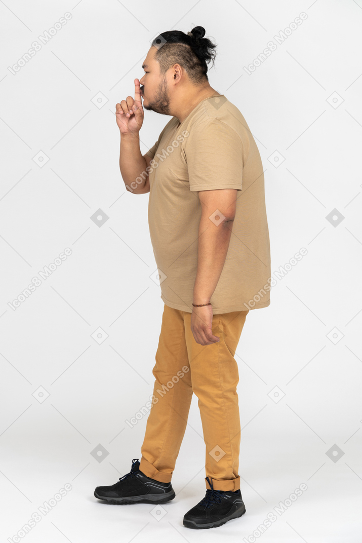 Homem asiático gordo fazendo gesto de silêncio no perfil