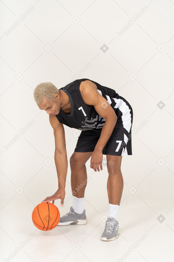 Three-quarter view of a young male basketball player touching ball