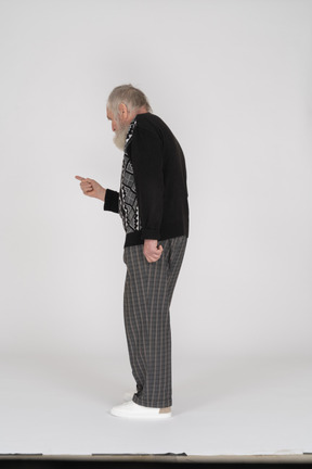 Side view of old man looking down and pointing with finger