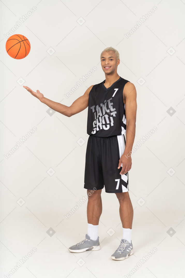 ボールを投げる若い男性のバスケットボール選手の4分の3のビュー