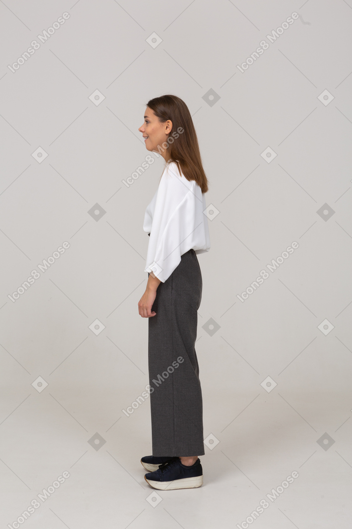 Vista lateral de una joven sonriente en ropa de oficina mirando a un lado