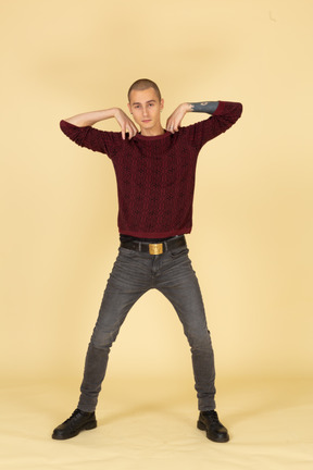 Front view of a young man in red pullover touching shoulders