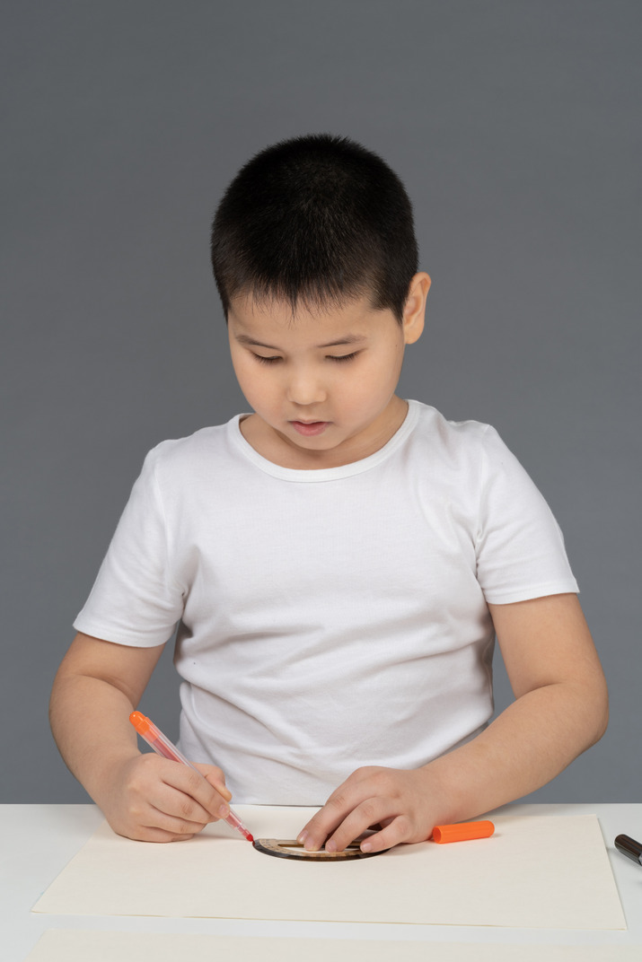 Asian boy drawing geometric shapes using triangular ruler