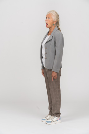 Vista laterale di una vecchia signora in abito che mostra la lingua