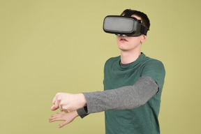 Young man in virtual reality headset grabbing something
