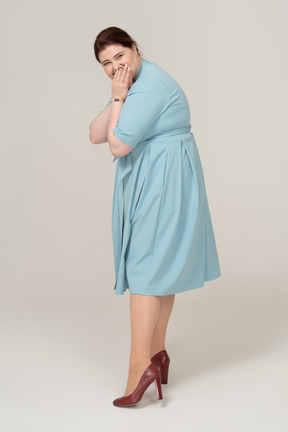 Side view of a happy woman in blue dress looking at camera