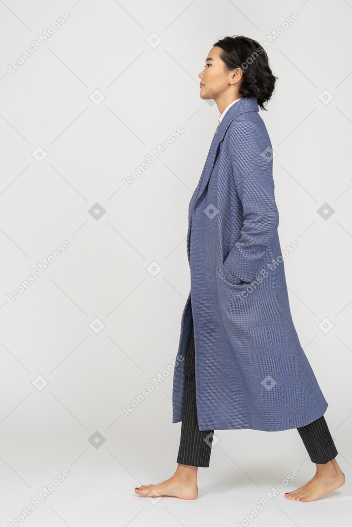 Vista laterale della donna in cappotto che cammina