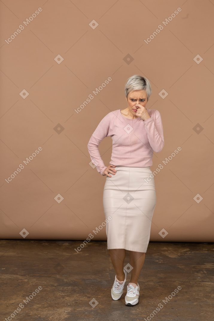 Vista frontal de una mujer pensativa en ropa casual tocando su nariz
