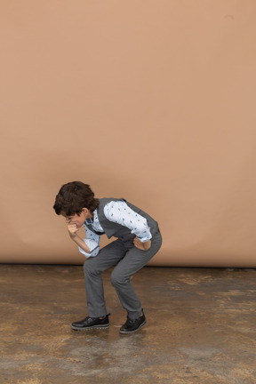 一个穿着西装的男孩蹲在下巴上握着拳头的正面图