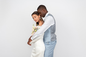 Bride and groom standing embraced with their eyes closed