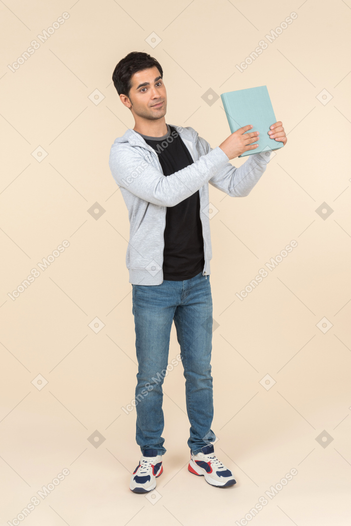彼が持っている本を指している若い白人男
