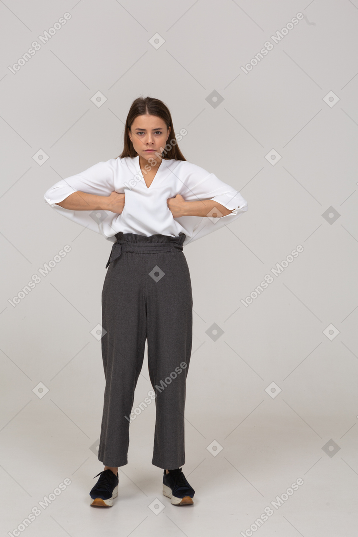 Front view of a young lady in office clothing putting hands on chest