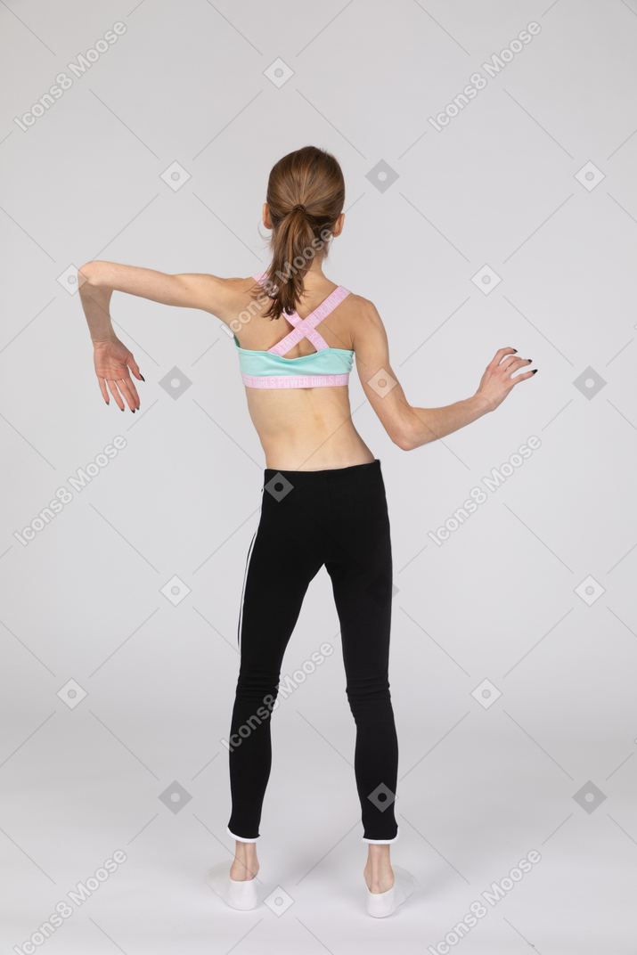Back view of a teen girl in sportswear tilting shoulders and making waves