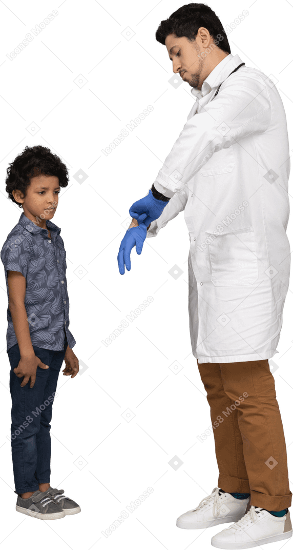 Doctor putting on surgical gloves while boy looking