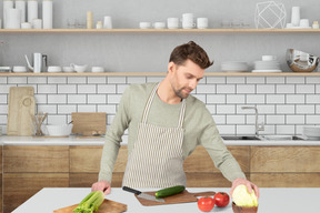 A man in an apron chopping vegetables on a cutting board