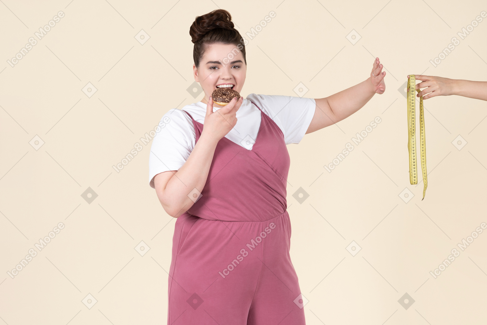 Young plus size woman in a fuchsia jumpsuit posing with food against a pastel yellow background