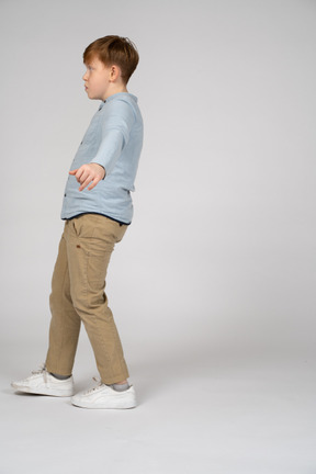 A young boy walking with his arms stretched out