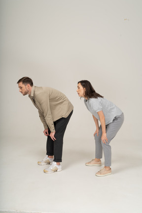 Jeune femme et homme accroupi avec les mains sur les genoux