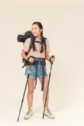 Joven excursionista mujer caminando con bastones de trekking