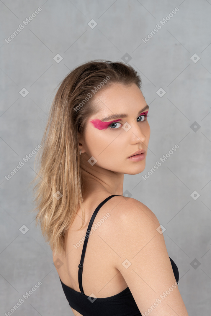 Mujer joven atractiva con maquillaje de ojos audaz girando la cabeza