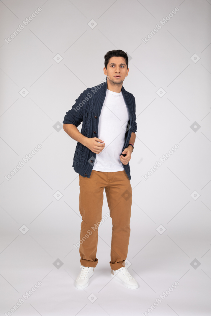 Man in pants and cardigan looking aside