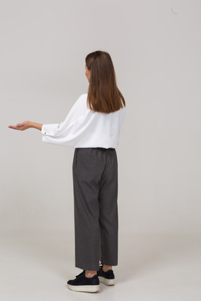 Vista posteriore di tre quarti di una giovane donna in abiti da ufficio che allarga le mani
