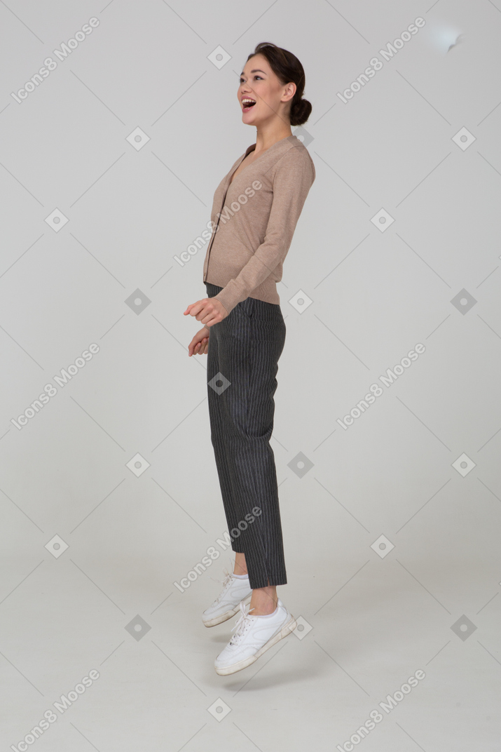 一个微笑的跳跃女士在米色套衫的侧视图