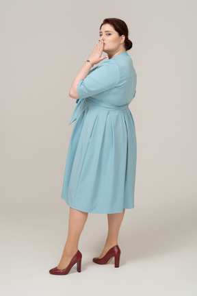 Side view of a woman in blue dress blowing a kiss