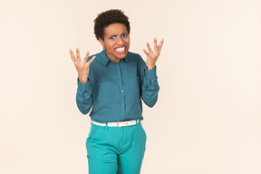 Black woman with a short haircut, wearing all blue, standing against a plain pastel background, looking emotional