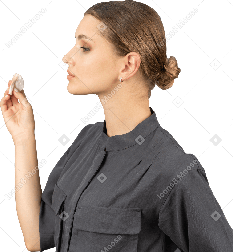Side view of a young woman in a jumpsuit removing concealer