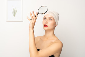 Portrait of a young woman holding up magnifying glass