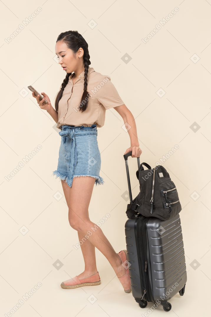 一位年轻女性旅行者查看手机的侧视图