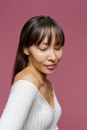 Three-quarter view of a shy middle-aged female looking down and smiling lightly