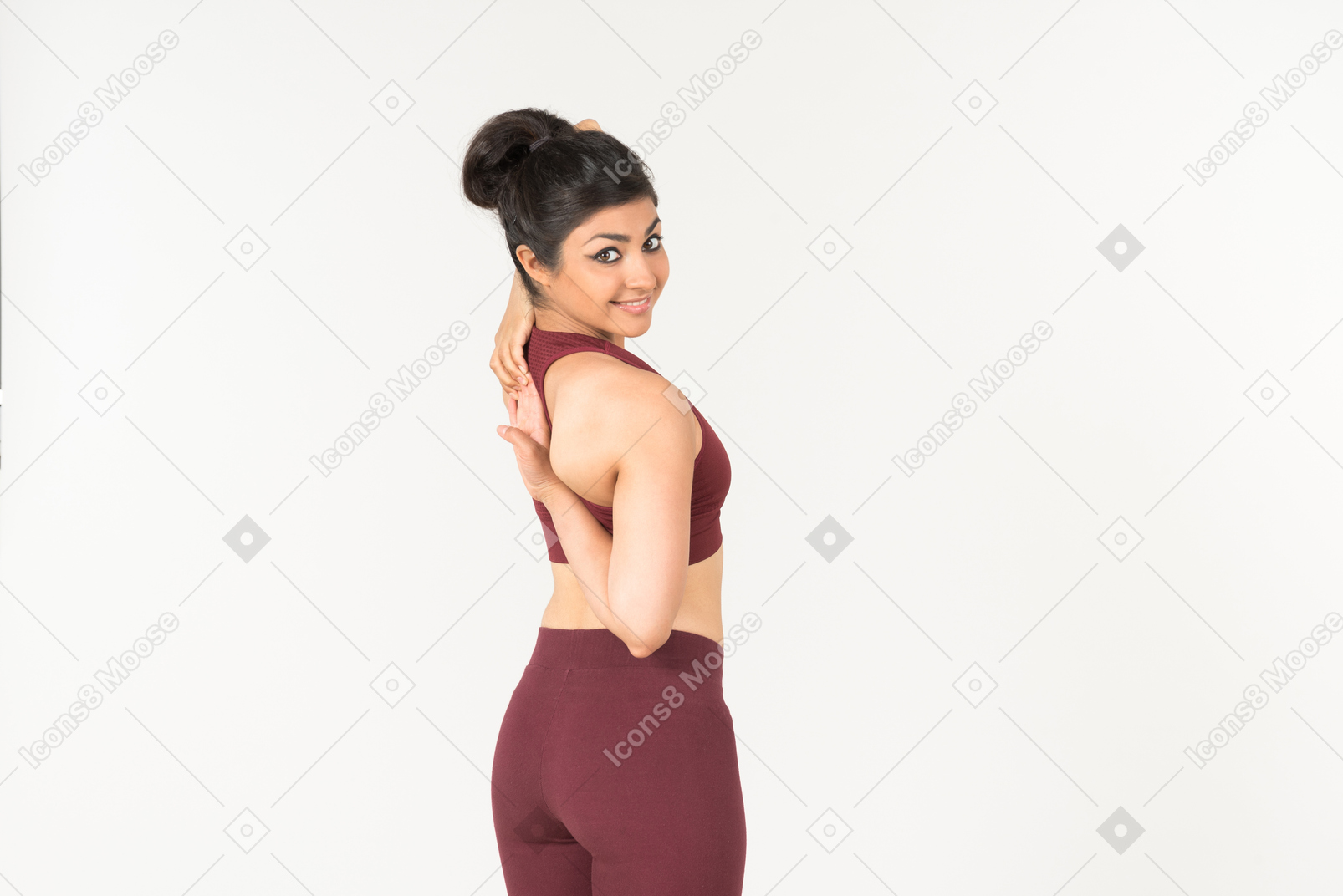Jovem mulher indiana no sportswear, segurando as mãos cruzadas atrás das costas