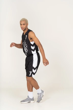 Vista lateral de un joven jugador de baloncesto masculino alejándose