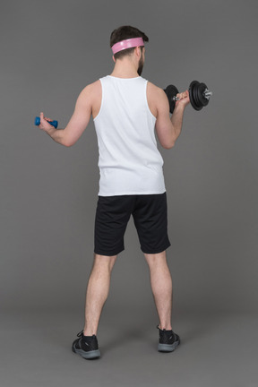 Man trying heavy and light dumbbell