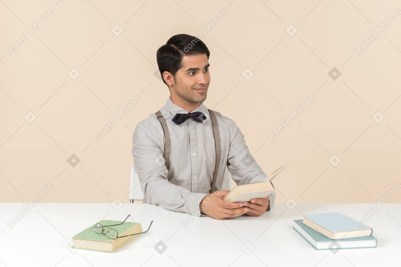 Jeune professeur assis à la table et lisant un livre