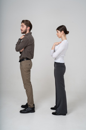 Vista lateral de una pareja joven mandona en ropa de oficina tocando el pecho