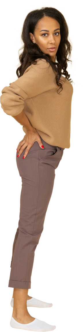 Vista lateral de una mujer joven de piel oscura poniendo las manos en el trasero