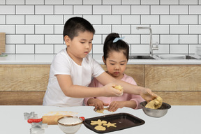 A boy and a girl are making cookies in a kitchen