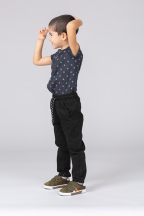 Side view of a boy standing with hand on head
