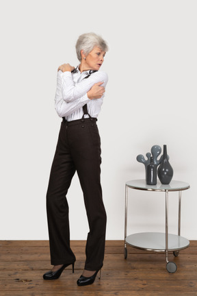 Front view of an old lady in office clothing embracing herself