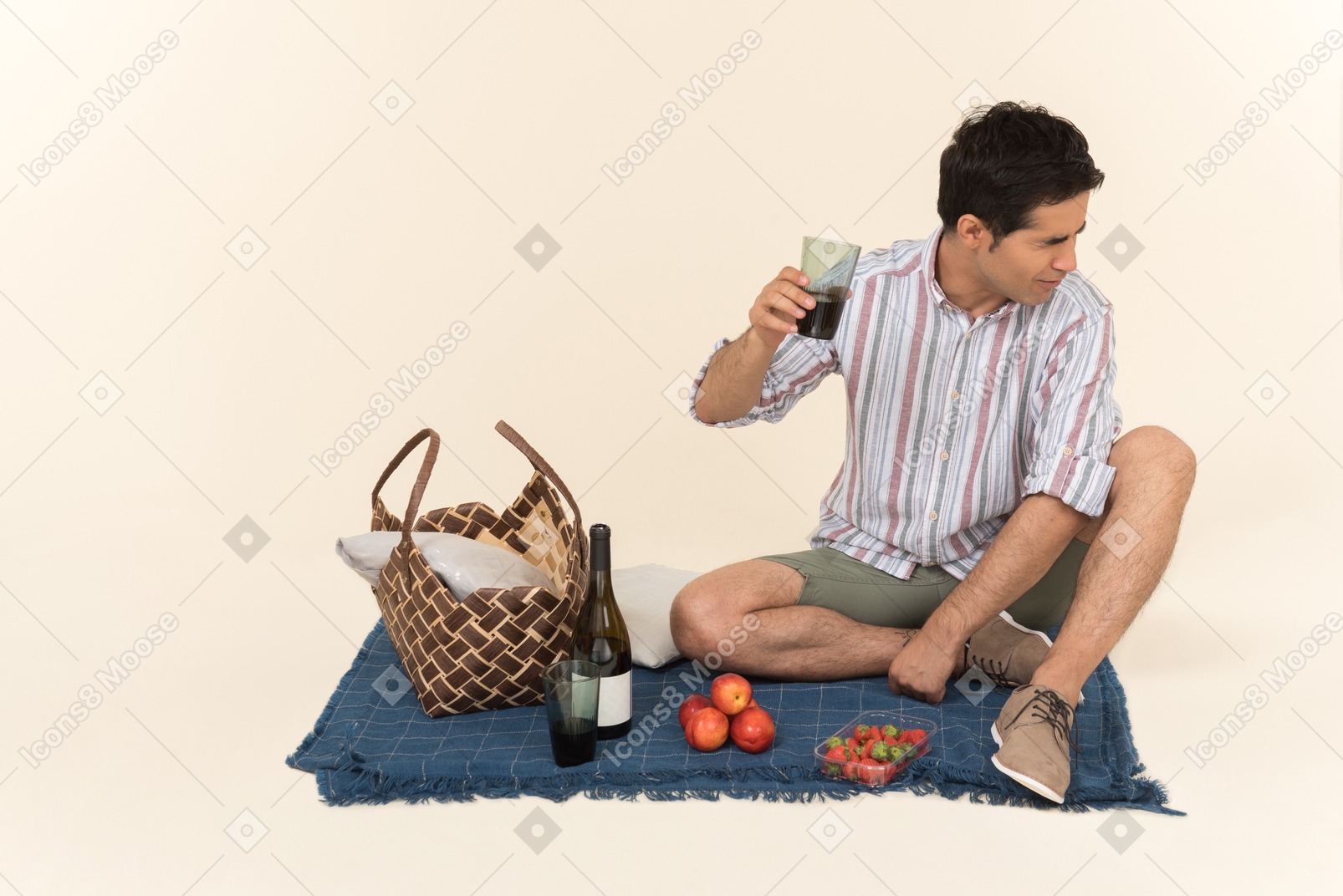 Молодой человек кавказской, держа бокал вина, сидя на одеяле