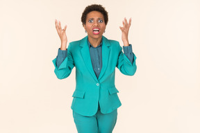 Black woman with a short haircut, wearing all blue, standing against a plain pastel background, looking emotional