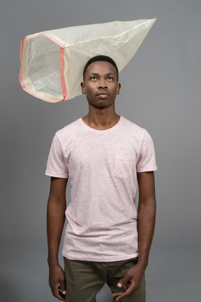 Retrato de un hombre joven con una bolsa de plástico volando cerca de él.