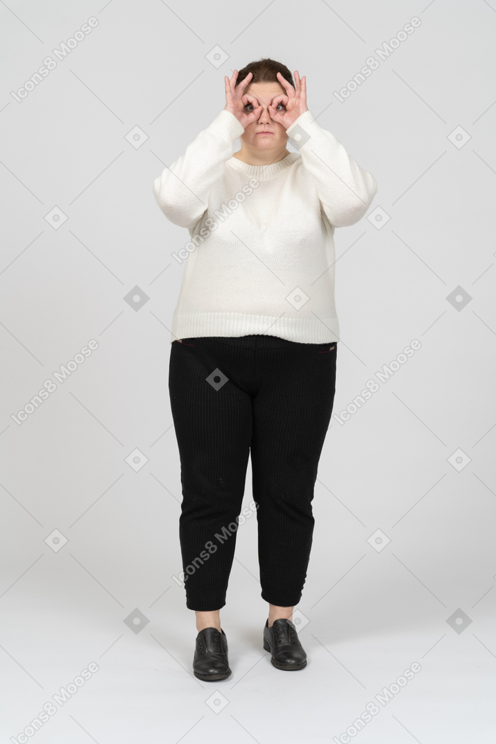 Plus size woman in casual clothes looking through imaginary binoculars