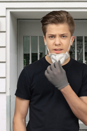 Young man taking off a face mask