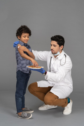 Doctor dando galletas al niño después de la vacunación.