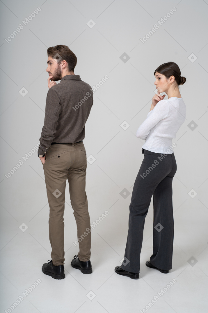 Three-quarter back view of a thoughtful young couple in office clothing touching chin